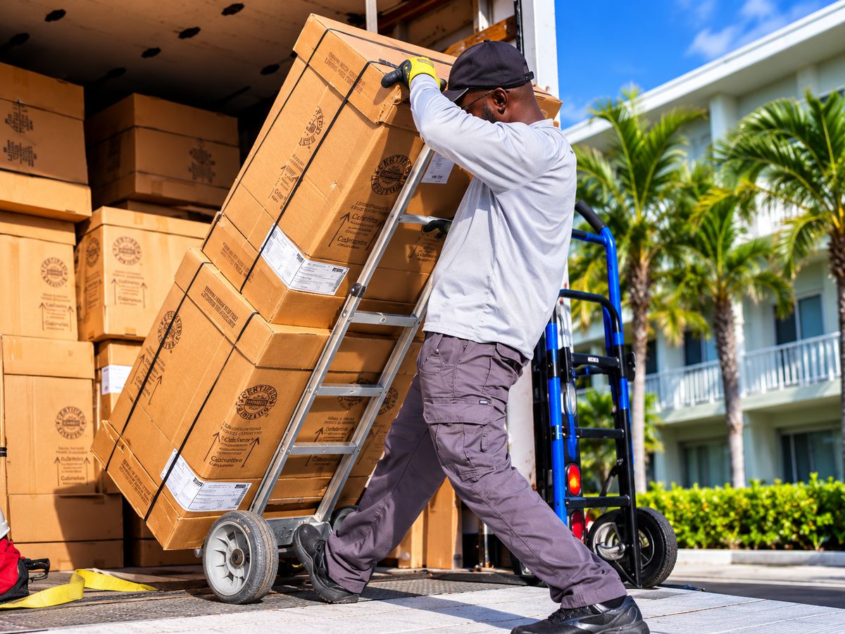 RC4 Logistics worker wheeling a loaded hand truck of boxes off a box truck for delivery